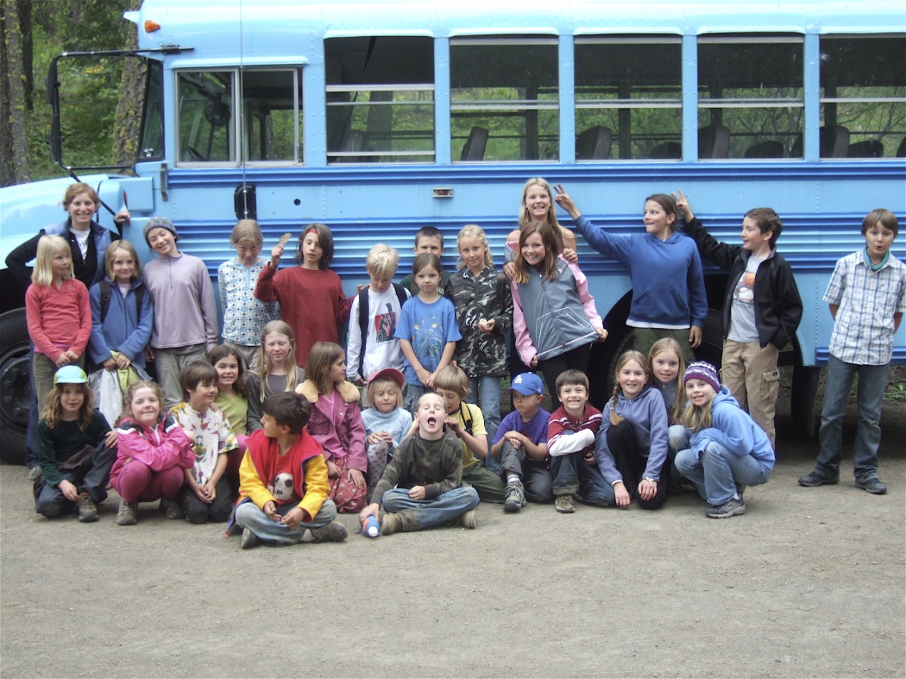 Sarah with students in front of a school bus